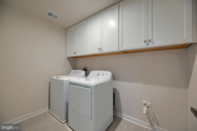 laundry room with light tile patterned flooring, cabinets, and washer and dryer