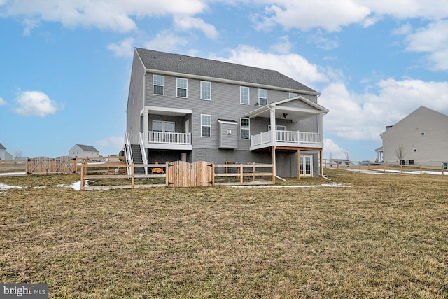 rear view of house featuring ceiling fan and a lawn