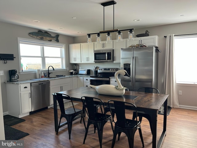 kitchen featuring stainless steel appliances, decorative light fixtures, sink, and white cabinets