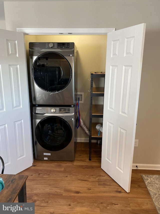 laundry room featuring hardwood / wood-style floors and stacked washer and clothes dryer