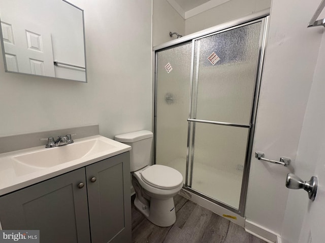 bathroom with toilet, vanity, a shower with shower door, and hardwood / wood-style flooring