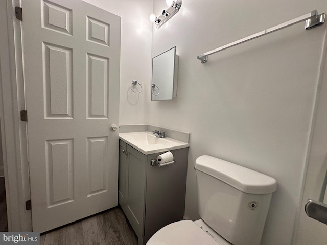 bathroom featuring toilet, vanity, and hardwood / wood-style flooring