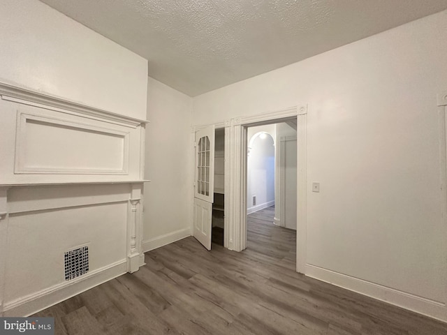 unfurnished room with a textured ceiling and dark hardwood / wood-style flooring