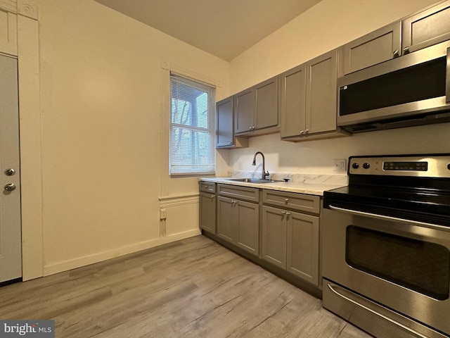 kitchen featuring gray cabinets, sink, appliances with stainless steel finishes, and light hardwood / wood-style flooring