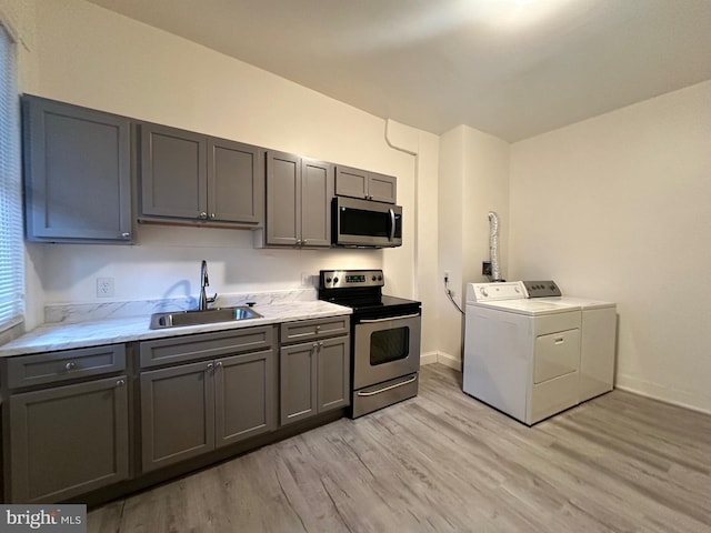 kitchen featuring independent washer and dryer, light hardwood / wood-style floors, sink, gray cabinetry, and stainless steel appliances