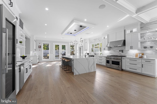 kitchen with an island with sink, white cabinets, backsplash, ornamental molding, and stainless steel appliances