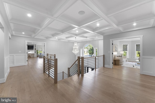 hallway with an inviting chandelier, coffered ceiling, beam ceiling, and hardwood / wood-style flooring