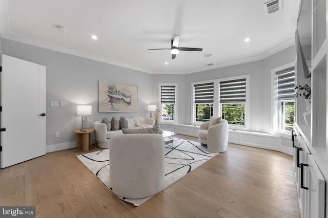 living room with crown molding, light hardwood / wood-style flooring, and ceiling fan