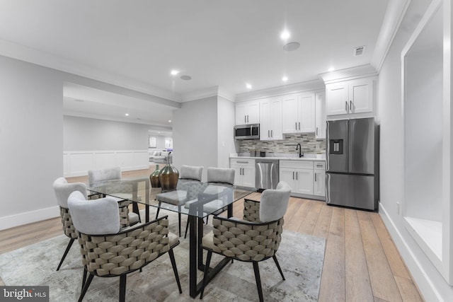 dining area with ornamental molding and light hardwood / wood-style floors