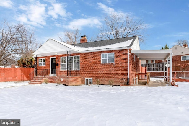 snow covered back of property with covered porch