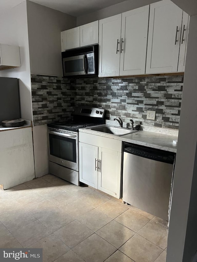 kitchen featuring stainless steel appliances, tasteful backsplash, sink, and white cabinets