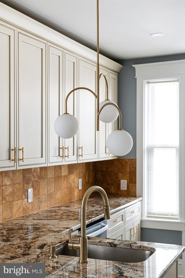 kitchen featuring decorative backsplash, dark stone counters, and sink