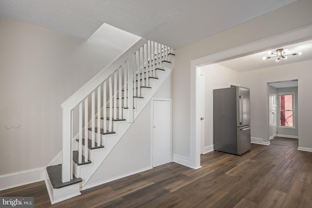 staircase featuring a textured ceiling, a chandelier, and hardwood / wood-style floors