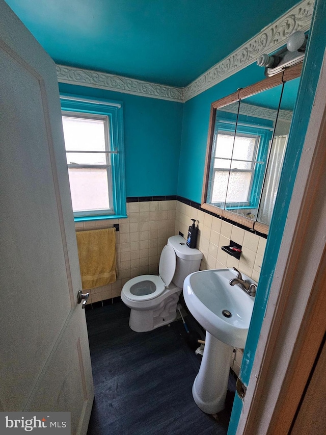 bathroom with hardwood / wood-style floors, a healthy amount of sunlight, tile walls, and toilet