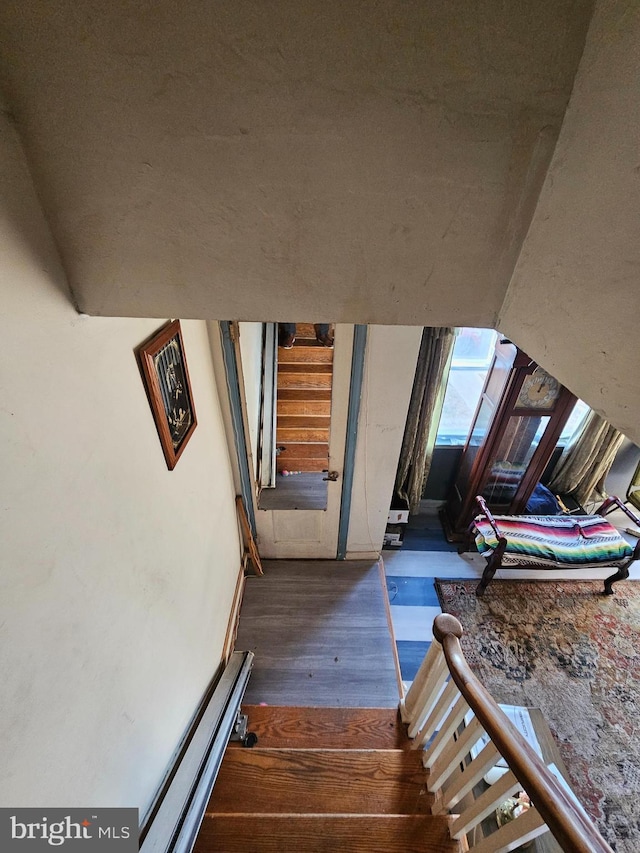 stairs featuring a baseboard heating unit and hardwood / wood-style floors