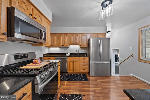 kitchen with stainless steel appliances, hardwood / wood-style floors, and dark stone counters