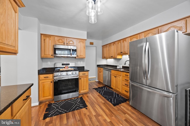 kitchen featuring stainless steel appliances, sink, and light wood-type flooring