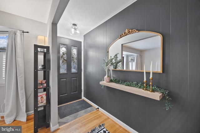 foyer entrance with light hardwood / wood-style floors and wood walls