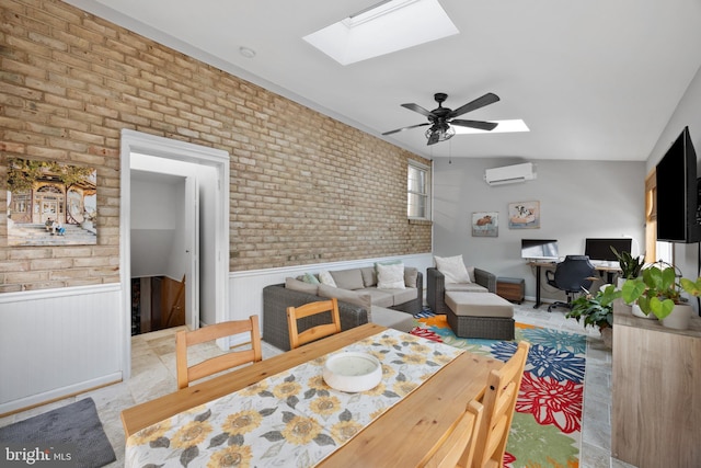 dining room featuring ceiling fan, brick wall, a wall mounted air conditioner, and vaulted ceiling with skylight