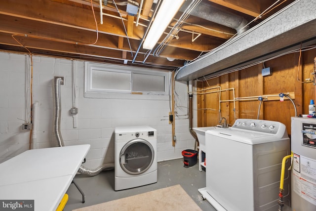 clothes washing area with separate washer and dryer, sink, and gas water heater