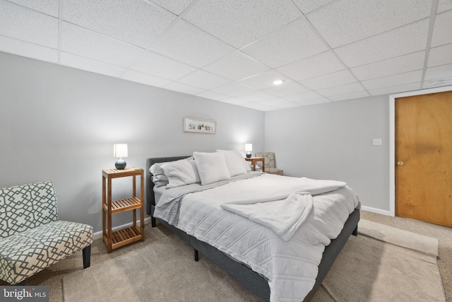 bedroom featuring light colored carpet and a drop ceiling