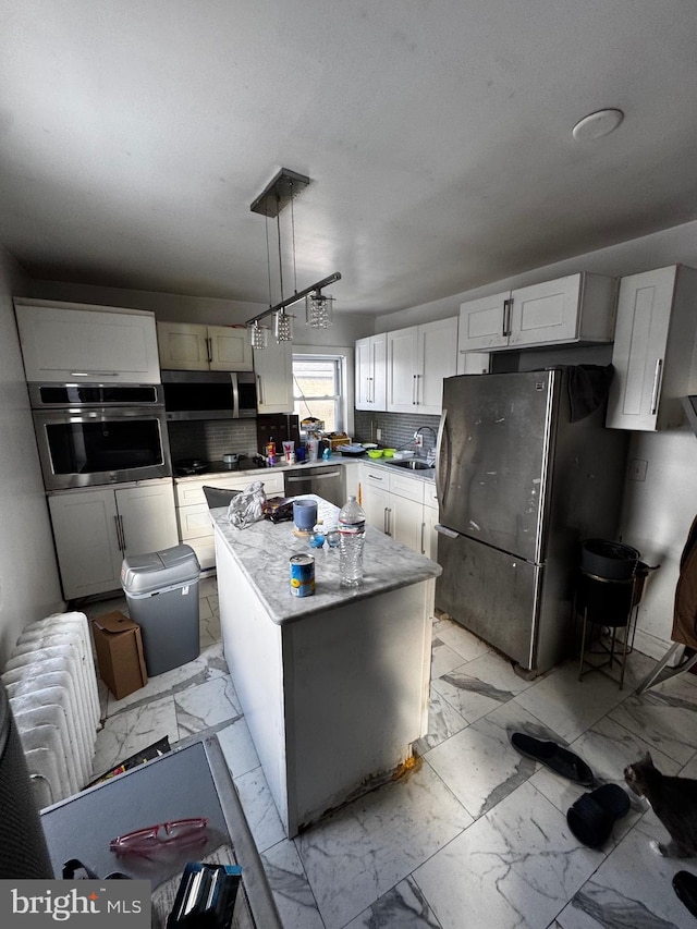 kitchen featuring appliances with stainless steel finishes, tasteful backsplash, a kitchen island, pendant lighting, and sink