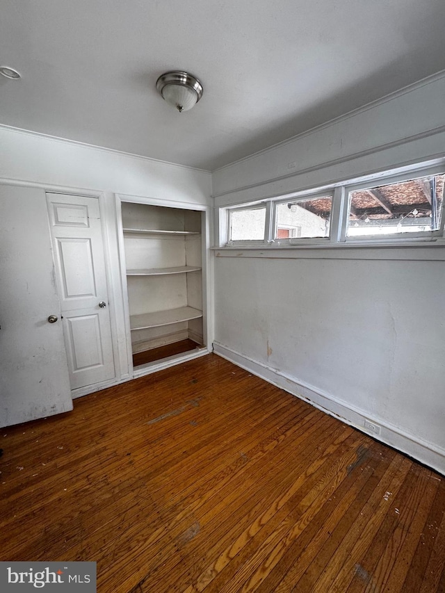 unfurnished bedroom featuring dark wood-type flooring and a closet