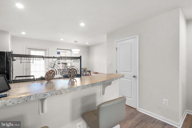 kitchen with dark hardwood / wood-style flooring, a kitchen bar, and black refrigerator