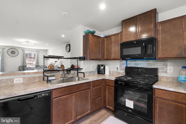 kitchen with black appliances, light hardwood / wood-style floors, sink, decorative backsplash, and kitchen peninsula