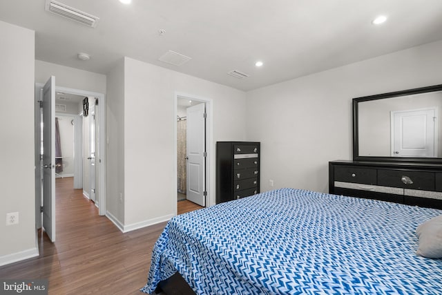 bedroom featuring connected bathroom and wood-type flooring