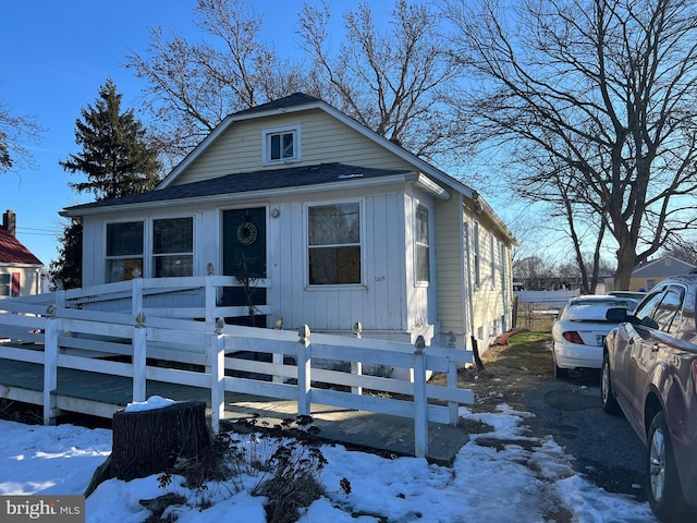 view of front of home with board and batten siding, a fenced front yard, and a shingled roof