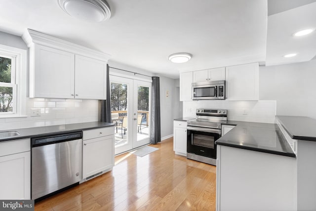 kitchen with french doors, appliances with stainless steel finishes, white cabinetry, and light hardwood / wood-style floors