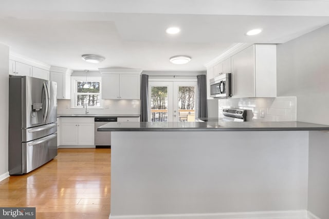 kitchen with white cabinets, appliances with stainless steel finishes, decorative backsplash, sink, and kitchen peninsula