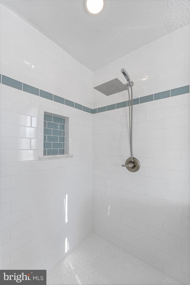 bathroom with a textured ceiling and a tile shower