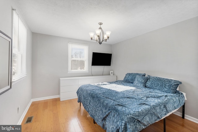 bedroom featuring a textured ceiling, a chandelier, and hardwood / wood-style floors