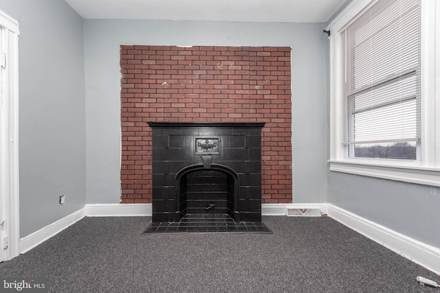 interior details featuring carpet and a tiled fireplace