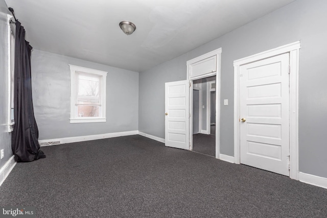 unfurnished bedroom featuring a closet and dark carpet