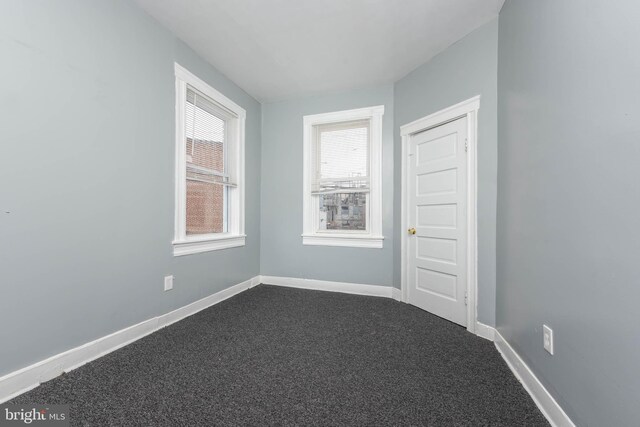 spare room with dark carpet