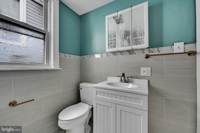 bathroom with toilet, tile walls, and vanity