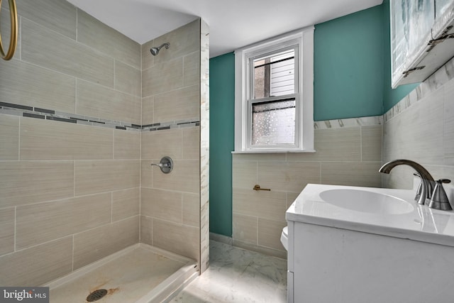 bathroom featuring toilet, a tile shower, tile walls, and vanity