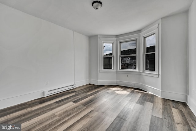 empty room featuring a baseboard heating unit, a wealth of natural light, and dark hardwood / wood-style floors