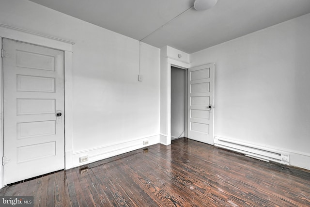 empty room featuring baseboard heating and dark hardwood / wood-style flooring