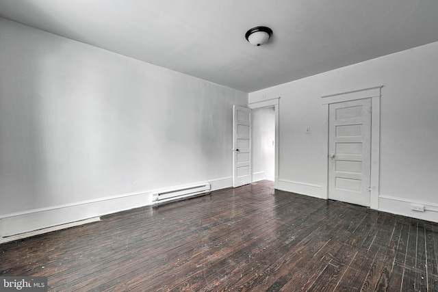 empty room featuring a baseboard heating unit and dark wood-type flooring