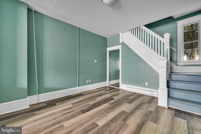 unfurnished room featuring wood-type flooring and a baseboard heating unit