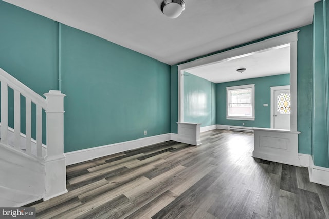 unfurnished living room featuring baseboard heating and hardwood / wood-style floors