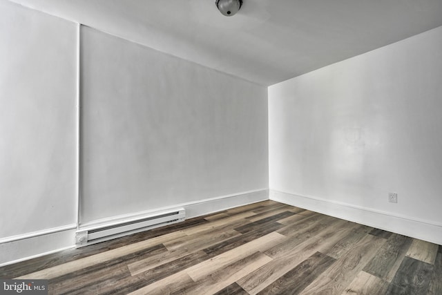 empty room featuring baseboard heating and wood-type flooring