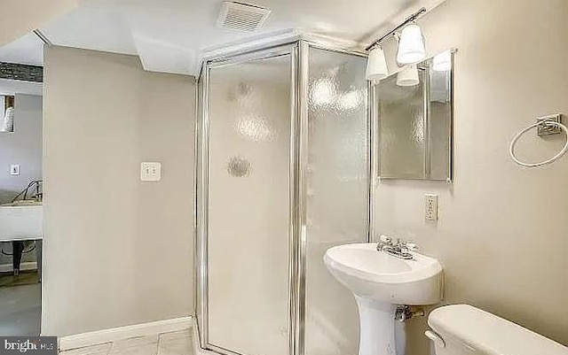 bathroom featuring toilet, an enclosed shower, and tile patterned flooring