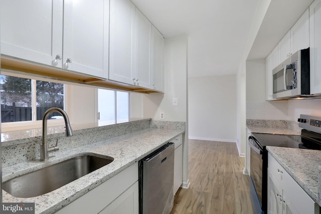 kitchen with light stone countertops, sink, white cabinets, and appliances with stainless steel finishes