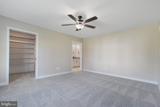 unfurnished bedroom with ceiling fan, a walk in closet, a closet, and light colored carpet