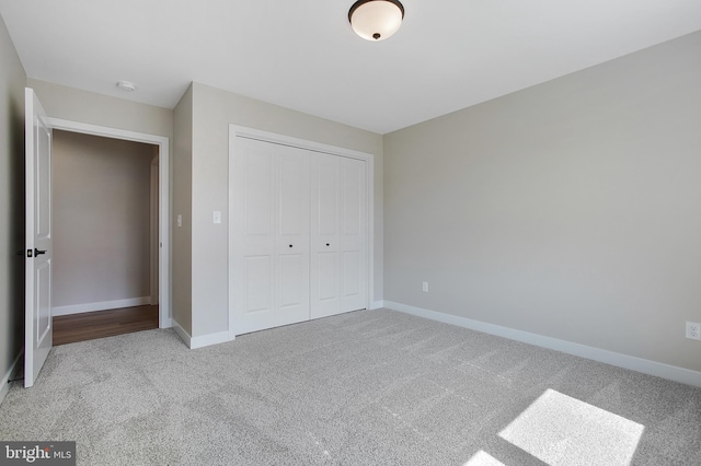 unfurnished bedroom with light colored carpet and a closet